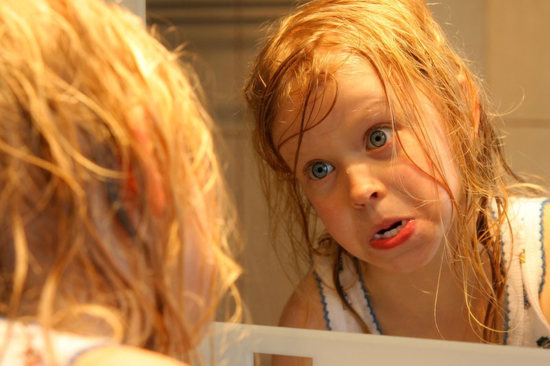 child making funny face in a mirror