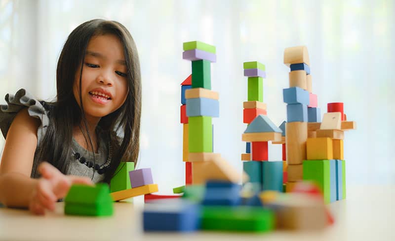 child stacking wooden blocks
