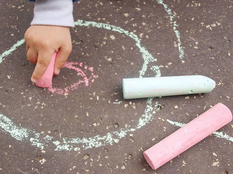 child drawing with chalk on sidewalk