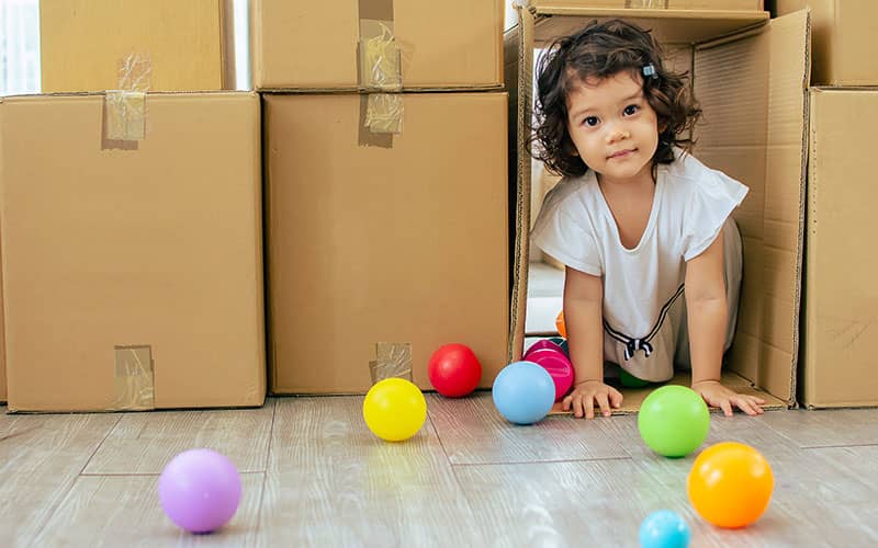 child playing with cardboard boxes and toy balls
