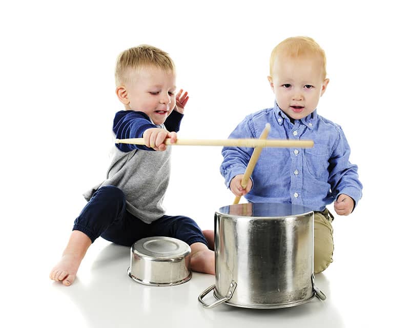 children hitting pots and pats with drumsticks