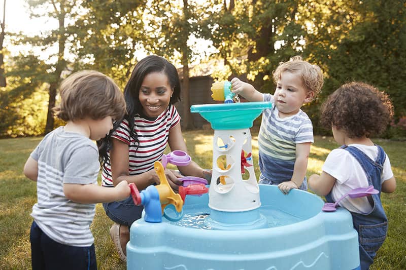 adult and children playing in toy fountain