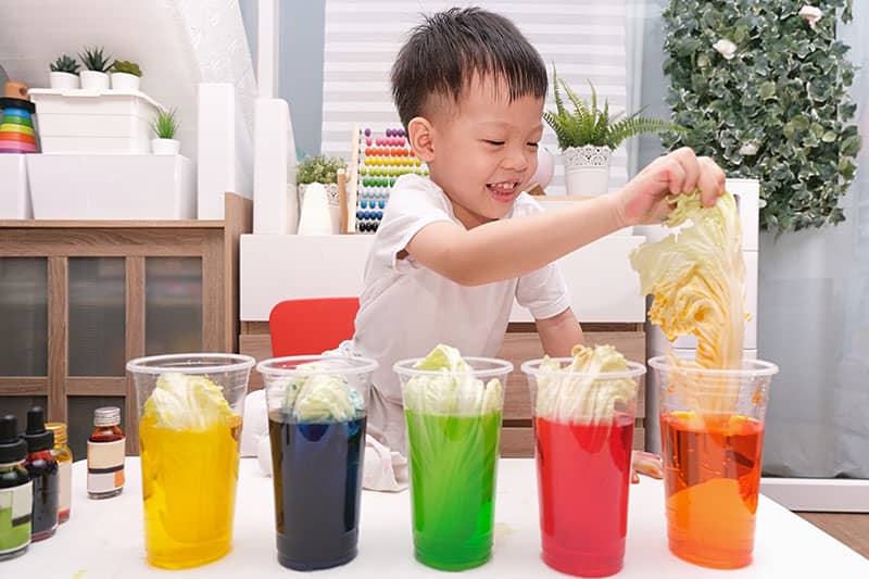 child playing with different colored waters